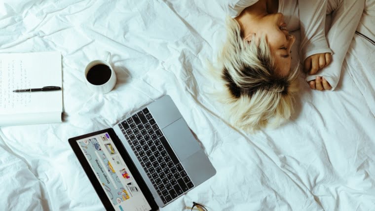 Young woman using laptop in bed and resting